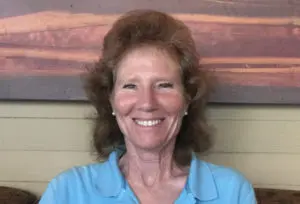 A woman with brown hair and blue shirt smiling.